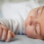 Newborn baby girl sleeping on blue sheets at home