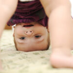 Baby boy playing upside down in bedroom