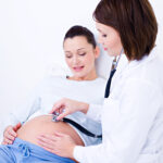 Female doctor  listen the stomach of a pregnant woman