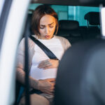 Young pregnant woman driving in car to hospital