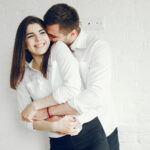 Cute couple on a kitchen. Pretty brunette in a white shirt.