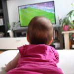 baby girl watching a soccer on TV