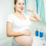 Portrait of beautiful pregnant woman brushing teeth in bathroom at morning