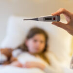 Mother checking body temprature on thremoeter in bedroom