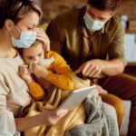 Caring parents communicating about daughter's medical condition with a  doctor via video call during coronavirus pandemic.