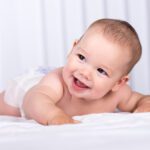 Portrait of a smiling crawling baby on the bed in the room.