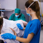 Medical team examining pregnant woman during delivery in operating room